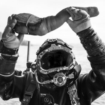 Image of a diver holding Geoduck aloft to show it's unusual size and shape.