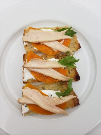 Image of El Capricho ventresca plated on crostiniw with creme fraiche and butternut squash