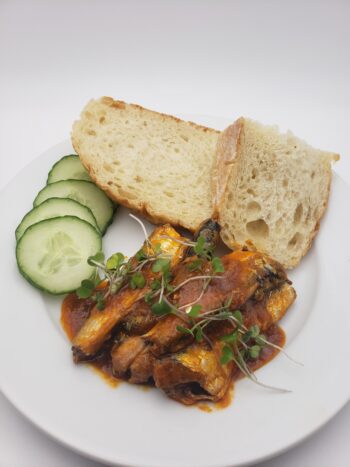 Image of JOse Gourmet sardines in tomato sauce plated with bread and cucumbers