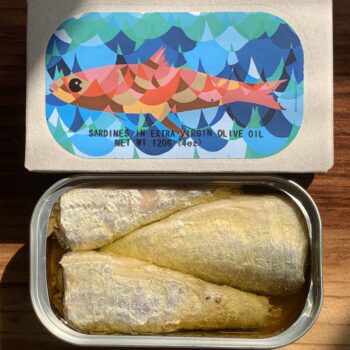 Image of the front of a package and an open tin of José Gourmet Sardines in Extra Virgin Olive Oil