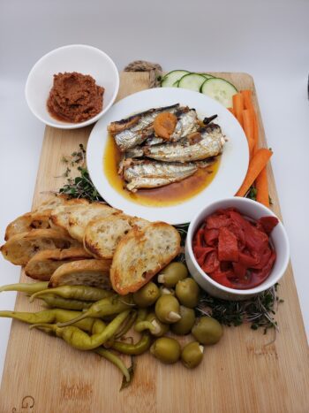 Image of Jacques Gonidec sardines with piri piri on a seacuterie board with pickled vegetables and crostini