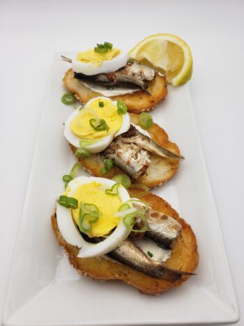 Image of King Oscar royal sardines with red bell pepper on crostini with hard boiled egg