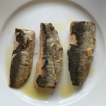 Image of the contents of a tin of Les Mouettes d’Arvor Sardine Fillets in Extra Virgin Olive Oil inverted onto a plate, separated and flipped over.