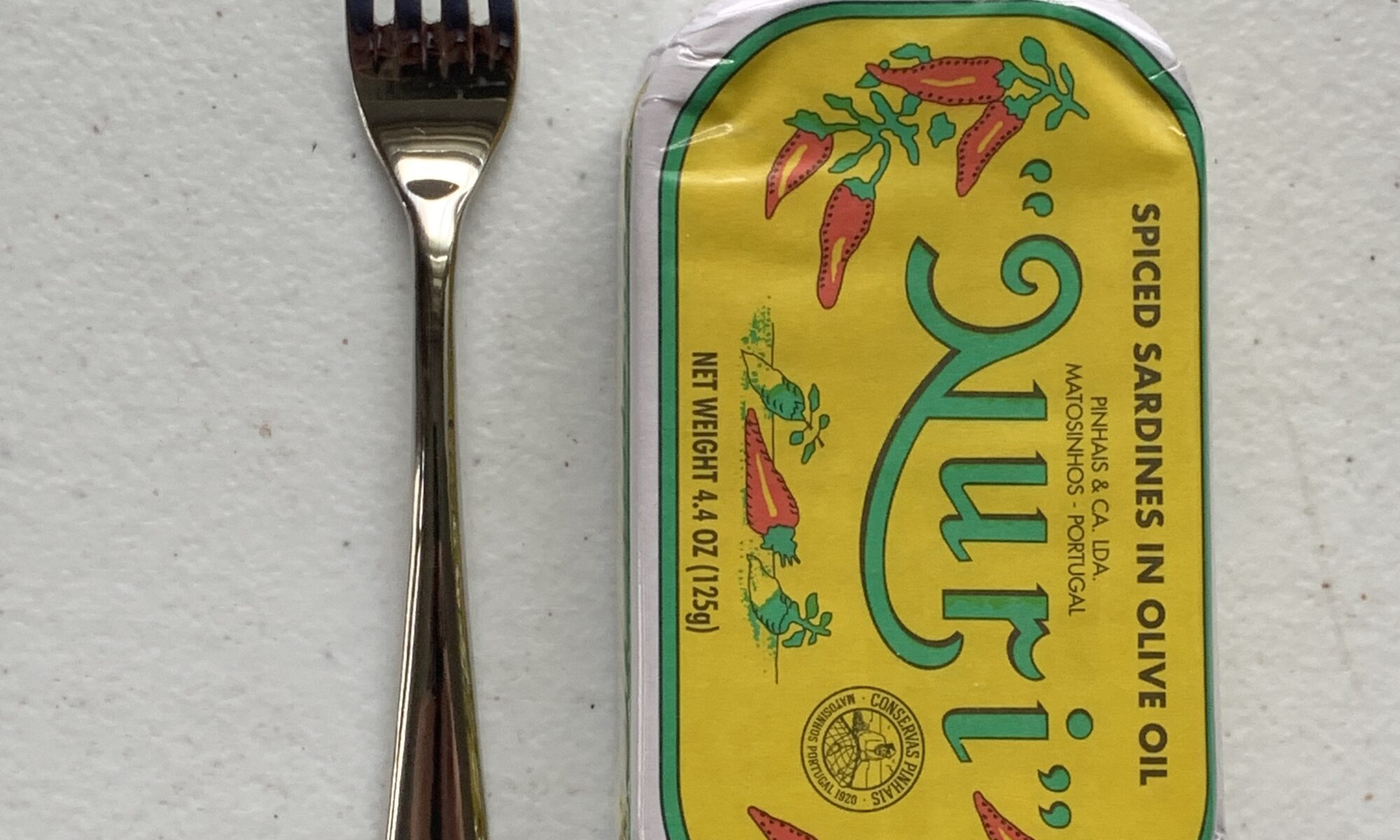 Image of a Cocktail Fork, Acopa Remy, Stainless Steel, Extra Heavy Weight next to a tin of sardines for scale.