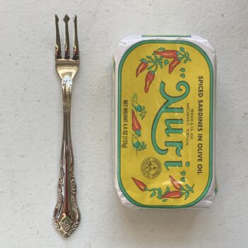 Image of a Cocktail Fork, Walco Discretion, Stainless Steel, Heavy Weight next to a tin of sardines for scale