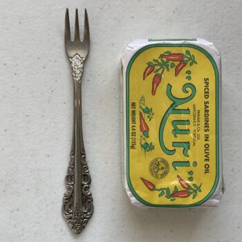 Image of a Cocktail Fork, Walco Classic Baroque (Fieldstone Finish), Extra Heavy Weight next to a tin of sardines for scale.