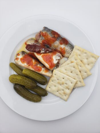 Image of bon appetit sardines in hot olive oil with saltines, hot sauce, and pickles
