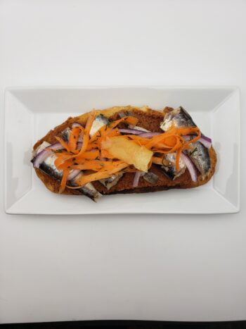 Image of Real Conservas sardinillas with lemon on toast with tapenade, pickled carrot, dill, and red onion