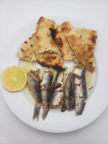 Image of Pollastrini vintage 2020 spicy sardines plated with pita bread and lemon