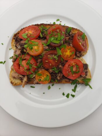 Image of Ferrigno sardines with tapenade on everything toast with tomatoes and persley