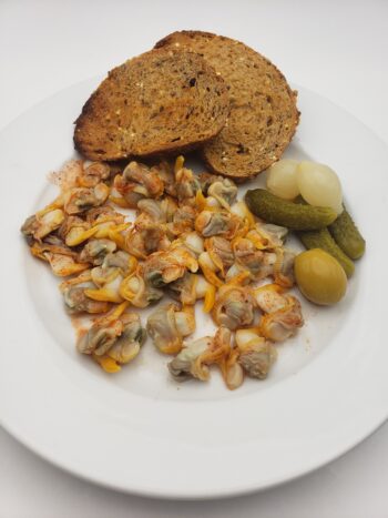 Image of Yurrita cockles in brine plated with multigrain toast, pickles, and espinaler sauce