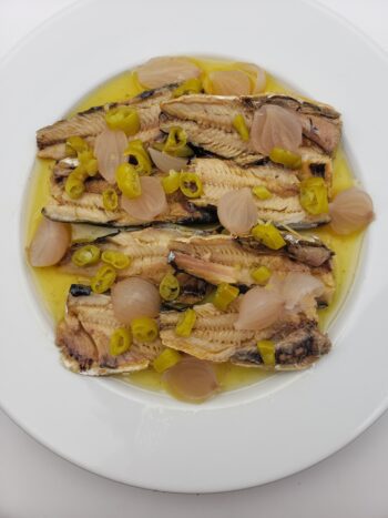 Image of Albert Menes boneless sardines plated with pickled onions nad guindillas