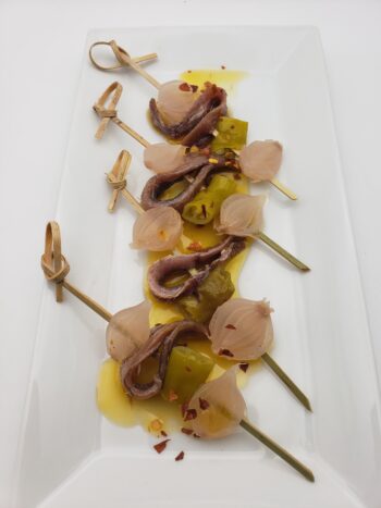 Image of Rizzoli anchovies in olive oil on skewers with pickled onions and guindillas