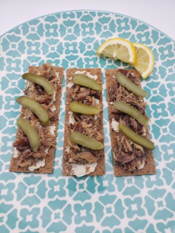 Image of Ocean's sweet smoked mackerel plated on crackers with cheese spread and pickles